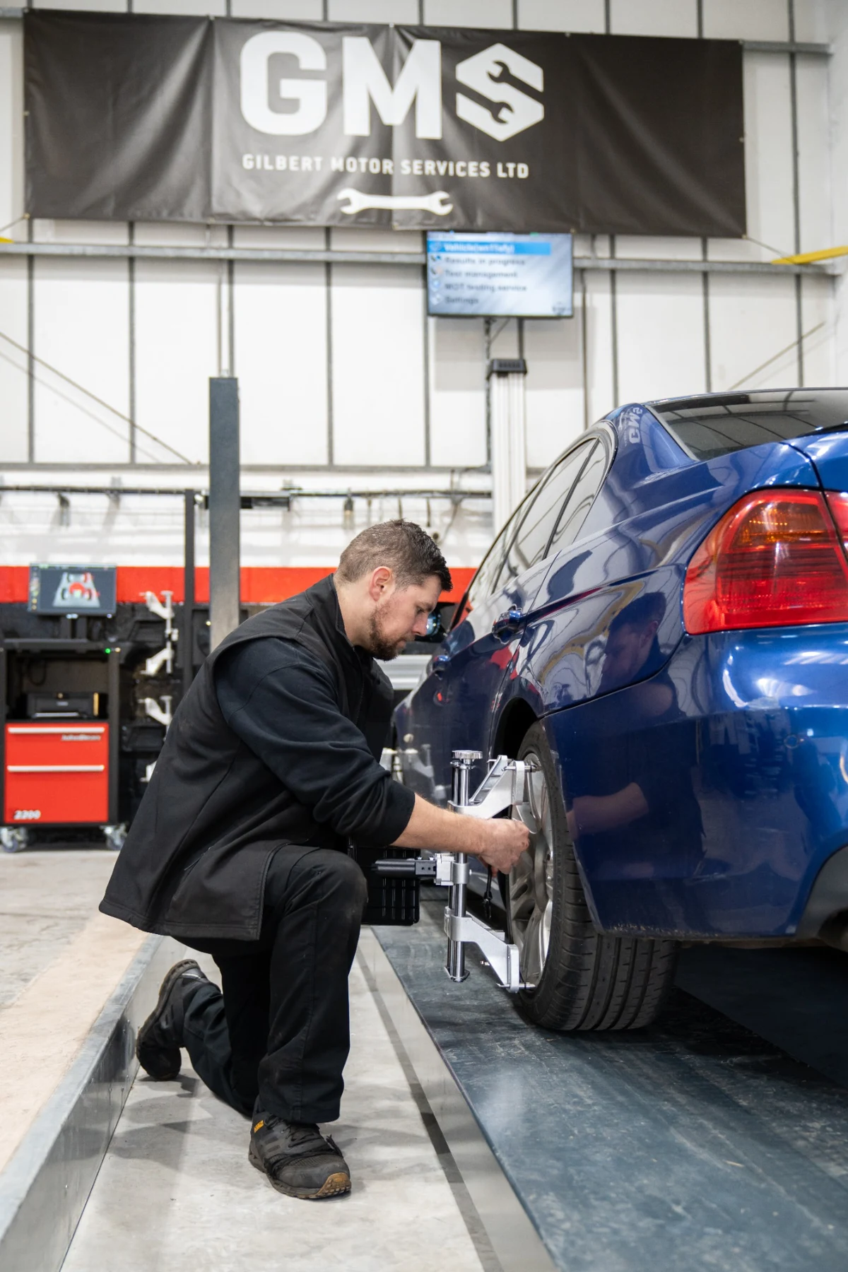Technician adjusting wheel alignment equipment on a vehicle